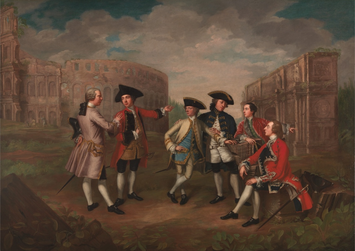 A painting depicting a group of six well-dressed 18th-century European gentlemen conversing and gesturing to each other in front of ruined classical architecture, including the Colosseum in Rome. The figures wear elaborate coats, waistcoats, breeches and tricorn or bicorn hats in shades of red, blue, cream, and brown. The background shows a cloudy sky above the stone ruins.