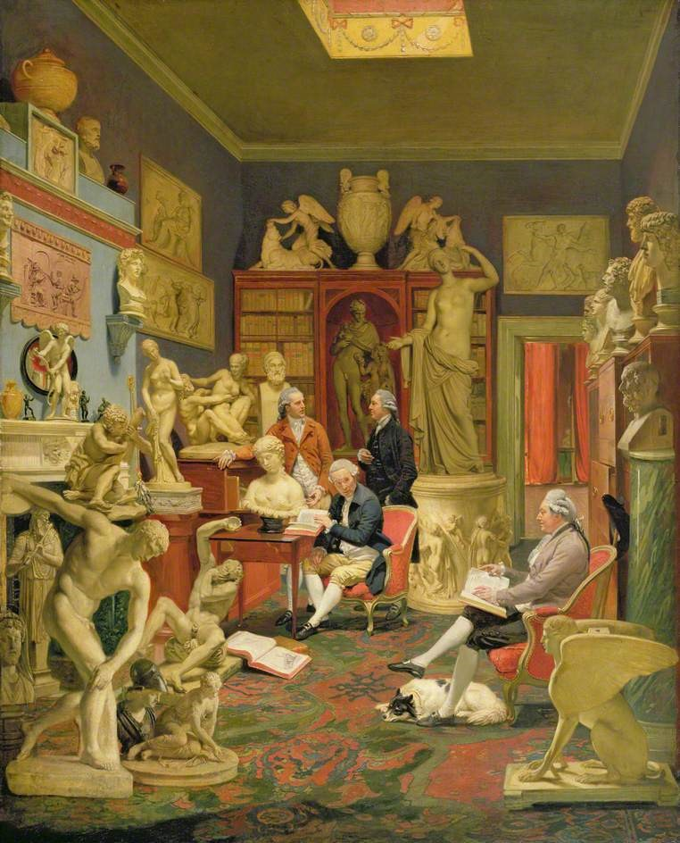 Interior scene of a sculptor's studio with four gentlemen surrounded by nude and clothed Classical marble statues, plaster casts, and busts. The room has a green ceiling, blue walls, and decorative carpet on the floor. Two men sits on chairs while the other two stand and converse.